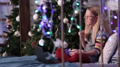 可爱的少女坐在床上在圣诞装饰的房间和吃爆米花，同时在笔记本电脑上看有趣的<strong>动画</strong>片