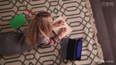 俯视图可爱的<strong>女</strong>学生躺在毯子上的地板上，做作业在作业本现代儿童