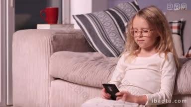 可爱的小<strong>女孩</strong>坐在沙发附近的地板上玩手机，微笑的孩子在家里使用手机