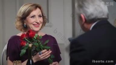 在<strong>结婚纪念</strong>日，快乐的妻子从她忠诚的丈夫那里收到一束红玫瑰美丽的高级女士闻着花束