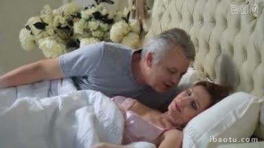 英俊的老人叫醒他美丽的妻子，低声说早安积极成熟的成年人躺在家里的床上