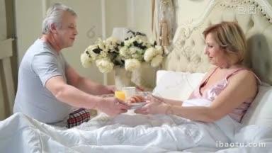 照顾老人的丈夫把早餐送到老年妇女在卧室的早上惊讶的妻子享受美味的早餐