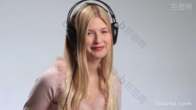 微笑美丽的女孩戴着耳机在白色背景上享受音乐，俏皮开朗的年轻女子涂着口红正在听音乐