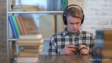 十几岁的学生带着耳机在他的智能手机上在线学习<strong>课程</strong>，在家里有吸引力的年轻男子浏览手机和听