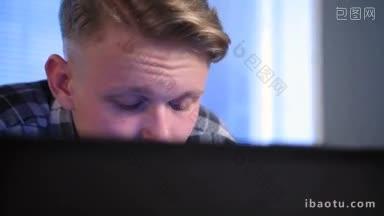 年轻专注的青少年在电脑前工作，半脸躲在笔记本电脑屏幕后面