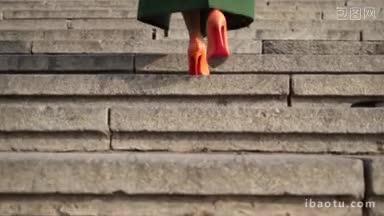 近距离拍摄完美女子的腿，穿着<strong>橙色高跟鞋</strong>，走在城市低段的石头楼梯上