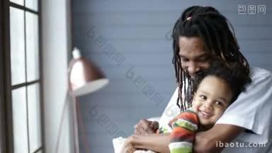 留着脏辫的微笑的非裔美国父亲拥抱着他蹒跚学步的混血儿，愉快地在家里共度时光