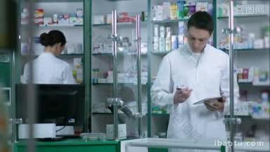 在药店<strong>工作</strong>的两名药剂师，前面是男药剂师，正在用平板电脑<strong>检查</strong>药品，前面是女药剂师