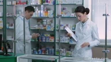 <strong>迷人</strong>的女药剂师与剪贴板和铅笔计数库存与同事在药房女药剂师妇女检查药品，而她