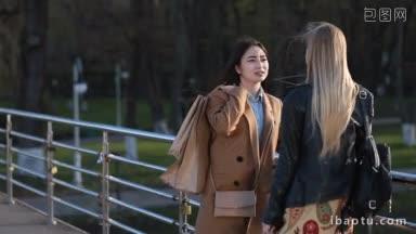 迷人的亚洲时尚女子肩扛<strong>购物袋</strong>站在人行天桥上与女友交流