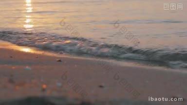 近景拍摄的海浪冲刷海岸在<strong>日落</strong>金色的<strong>太阳</strong>反射在水中