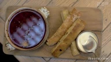 特写镜头的女人吃罗宋汤，酸奶油和面包在餐厅的木板