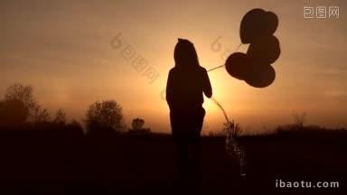 小女孩的剪影与<strong>彩色</strong>气球走在草地在发光的晚霞后景