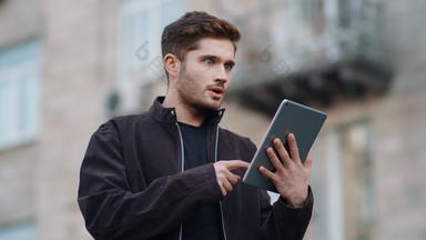 惊讶男人。平板电脑屏幕在户外快乐的家伙数字平板电脑