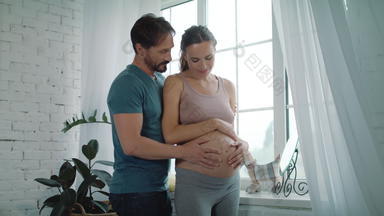 <strong>快乐</strong>丈夫持有肚子怀孕了妻子首页怀孕了夫妇拥抱