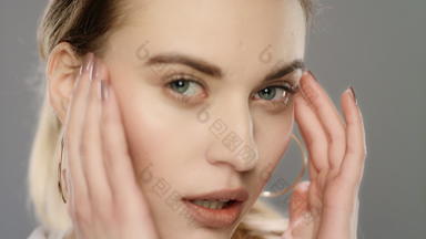 年轻的女人触碰脸皮肤慢运动女人面部按摩