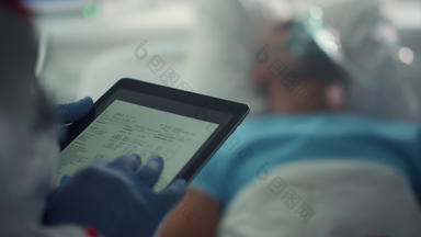 医生持有平板电脑屏幕检查病人医疗历史病房特写镜头