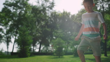 快乐男孩玩足球阳光公园孩子使足球锻炼自然