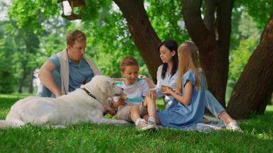 快乐<strong>家庭</strong>喂养白色狗野餐人heve有趣的绿色草