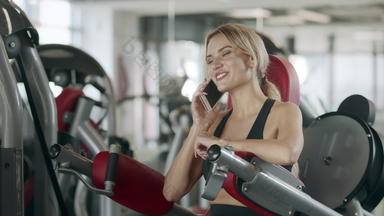 快乐的女人会说话的移动电话健身培训机体育运动健身房