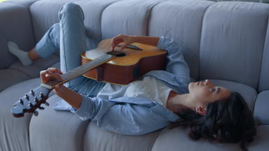 女孩玩吉他沙发放松音乐家玩和弦声吉他