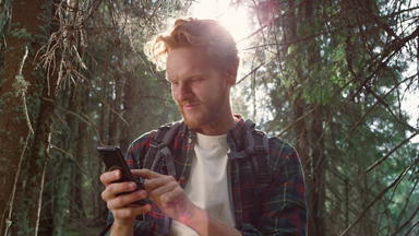旅行者智能手机森林红色头发的人男人。发短信消息手机