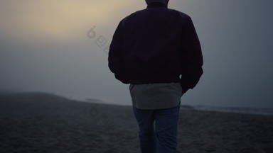 年轻的男人。走桑迪海滩早....雾孤独的的家伙海地平线