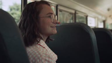 微笑青少年女孩坐着学校公共汽车会说话的朋友<strong>学生聊天</strong>