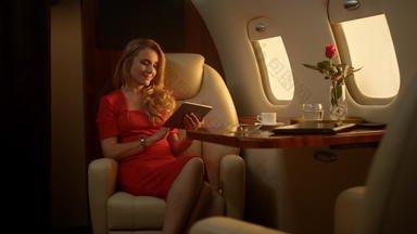 微笑女商人享受平板电脑电脑奢侈品私人飞机阳光