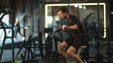 急切的体育运动男人。培训健身脚踏车健身房适合男人。有氧运动体育运动俱乐部