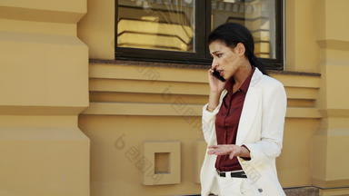 愤怒的女商人会说话的智能手机在户外女人走街