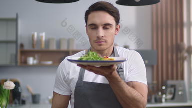 男人。<strong>烹饪</strong>闻沙拉首页厨房快乐的老板展示健康的食物