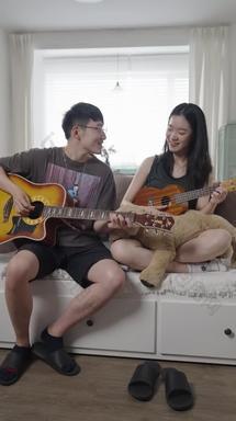 年轻情侣在家里弹吉他实拍