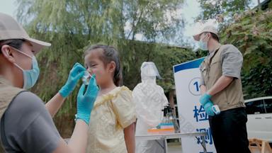 社区志愿者帮小女孩戴口罩社区看护实拍素材