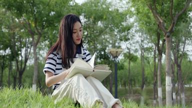 坐在草地上看书的大学生草地自然清晰实拍
