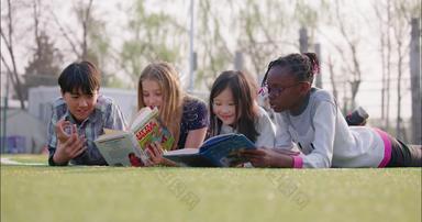 多种族<strong>儿童</strong>趴在草地上<strong>看书</strong>12岁到13岁宣传素材