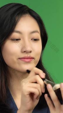 化妆的年轻商务女士化妆刷绿色背景视频素材
