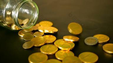 特写镜头生活黄金硬币黑色的表格旋转一分钱黄色的硬币下降了Jar