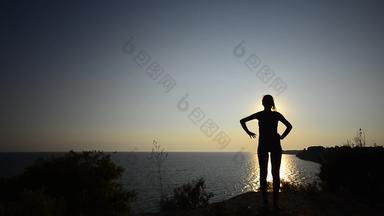 轮廓年轻的青少年女孩锻炼日落海洋海滩日落背光青少年锻炼