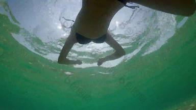 <strong>水</strong>下低角视图年轻的女人游泳平静海<strong>水</strong>表面背光夏天太阳闪亮的射线