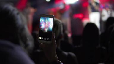 女孩手相机电话图片视频生活音乐会智能手机记录生活音乐节日照片前面音乐会阶段快乐青年奢侈品聚会，派对