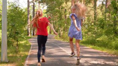 女朋友运行跳通路绿色夏天公园无忧无虑的女孩青少年有趣的夏天由阳光明媚的一天