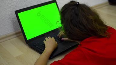 女孩移动PC计算绿色铬关键股票视频多莉变焦拍摄快乐年轻的青少年打字移动PC铺设地板上