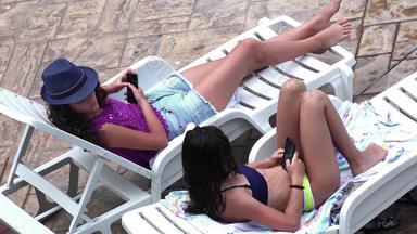 快乐年轻的女孩冲浪社会网络智能<strong>手机</strong>说谎池塑料床上