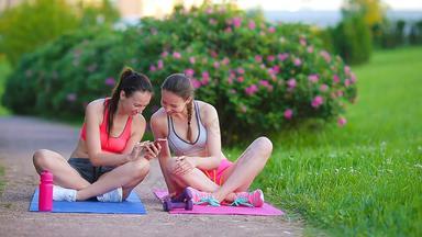 年轻的活跃的健身女性练习在户外智能手机运动女孩玩体育纳鲁尔公园