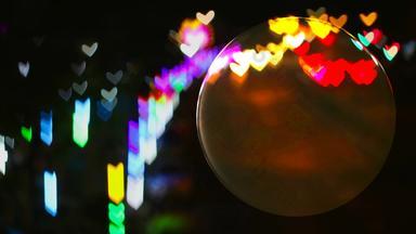 水晶球玻璃地板上心形的彩虹灯街反映了球表面
