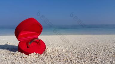 <strong>黄金</strong>建议环红色的天鹅绒心形状环盒子沙子清晰的水波崩溃海岸backgroundin夏威夷