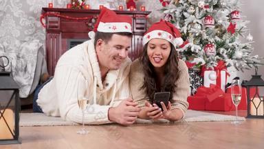 微笑夫妇坐着地板上购物在线智能手机圣诞节装饰房间