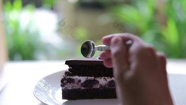 手勺子减少黑暗巧克力蛋糕樱桃酱汁美味的美味的甜点白色板自制的面包店糕点