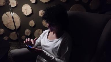 紧张女人问题冲浪网络智能手机黑暗坐着扶手椅拉普姆晚上